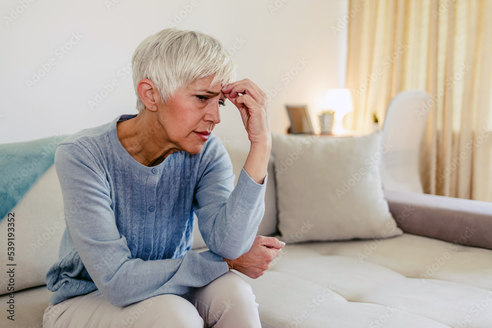 Head shot close up portrait thoughtful middle aged retired woman worrying about personal health problems. Upset older female retiree thinking of family troubles, feeling lonely, sitting at home.