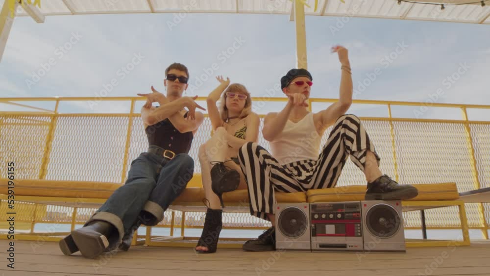 Low angle stab shot of glamorous 80s style team of voguers dancing at camera outdoors