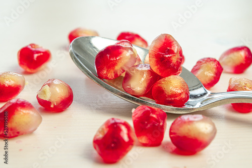 Pomegranate arils in bowl and spoon beside.
 photo