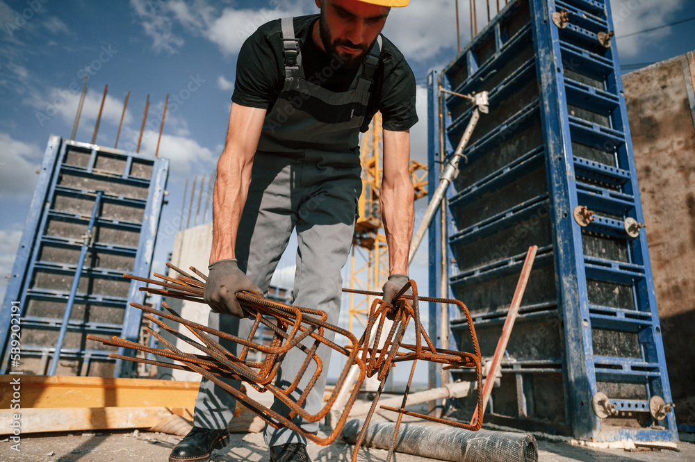 Metal pieces covered in rust. Man in uniform is working on the construction site Metal pieces covered in rust. Man in uniform is working on the construction site
