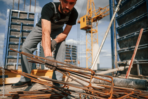 Metal pieces covered in rust. Man in uniform is working on the construction site