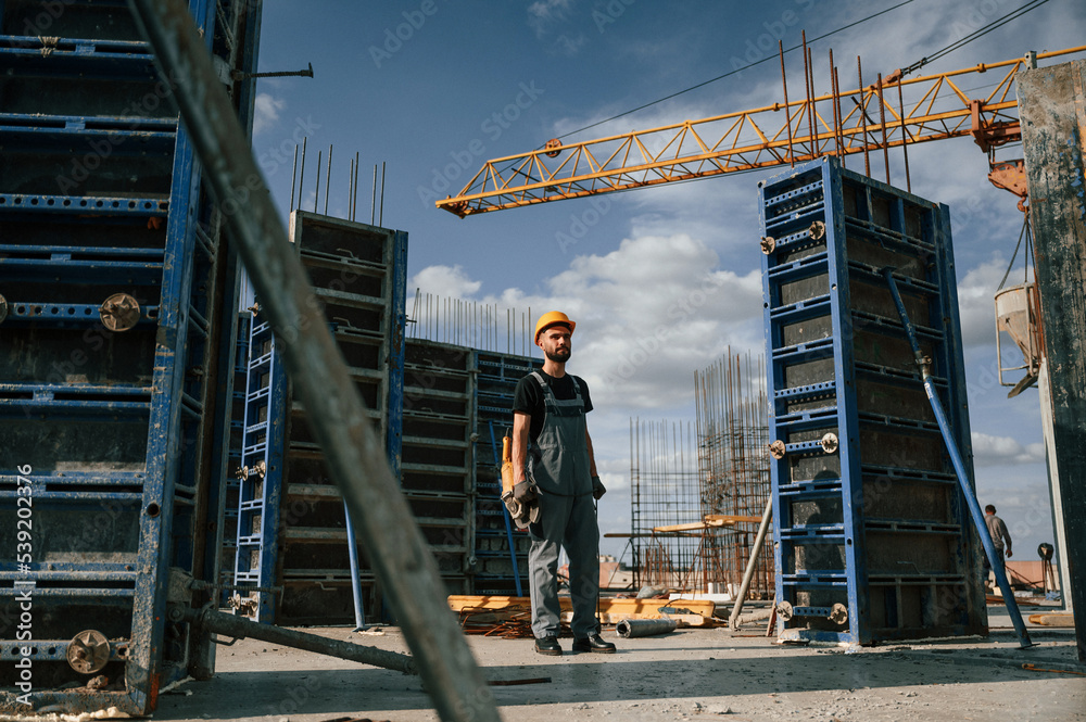 Standing with grinding machine in hands. Man in uniform is working on the construction site Standing with grinding machine in hands. Man in uniform is working on the construction site