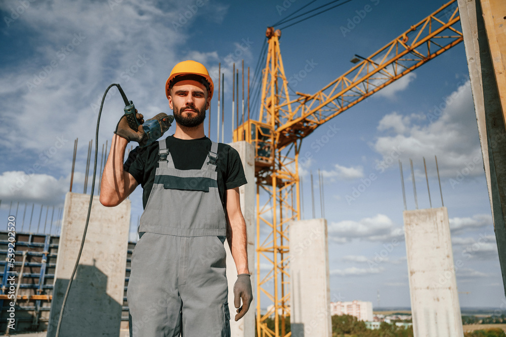 Portrait of man that is in uniform with the drill on the construction site
