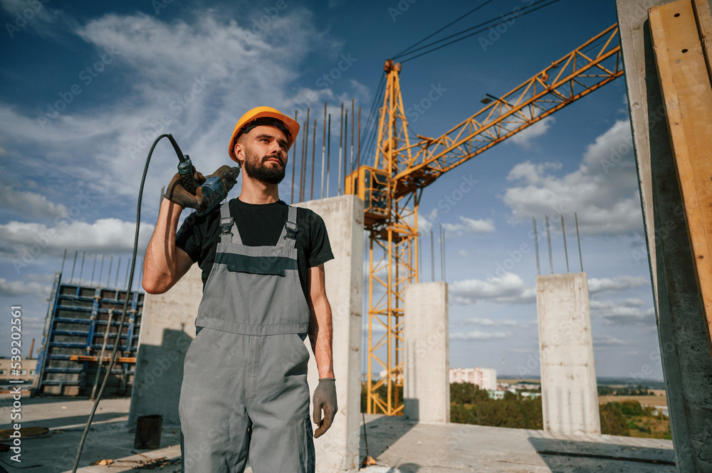 custom made wallpaper toronto digitalStanding and holding drill. Man in uniform is working on the construction site