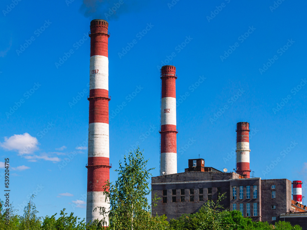 Black smoke comes out of the production high pipe. Industrial zone of the factory territory. Pipes in the factory and a large steel tank with fuel. Production technologies at the enterprise. Black smoke comes out of the production high pipe. Industrial zone of the factory territory. Pipes in the factory and a large steel tank with fuel. Production technologies at the enterprise.