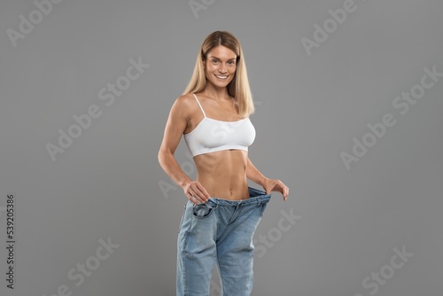Weight Loss Result. Happy Young Woman Posing In Oversized Jeans