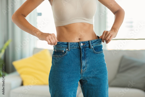 Slim Woman Posing Wearing Oversized Skinny Jeans At Home, Cropped