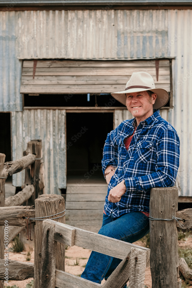 Happy farmer leans against sheep yards. Happy farmer leans against sheep yards.