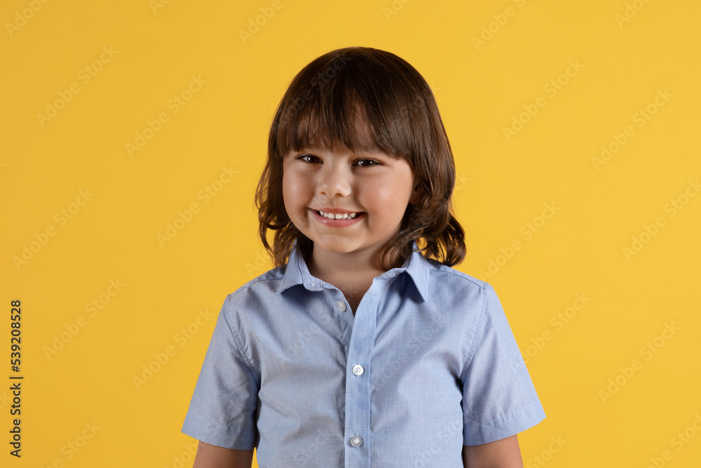 Pretty kid. Adorable little boy smiling to camera, feeling carefree and happy, orange studio background Pretty kid. Adorable little boy smiling to camera, feeling carefree and happy, orange studio background