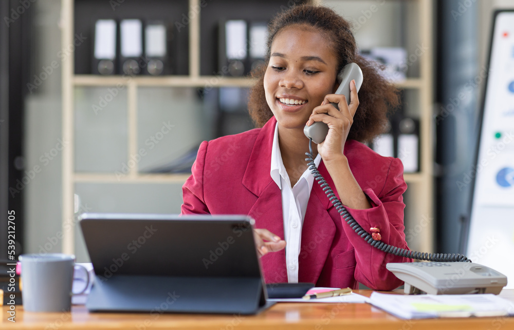 Young businesswoman cheerful african american lady working at workplace office, workdesk with laptop financial documents having phone conversation, copy space Young businesswoman cheerful african american lady working at workplace office, workdesk with laptop financial documents having phone conversation, copy space