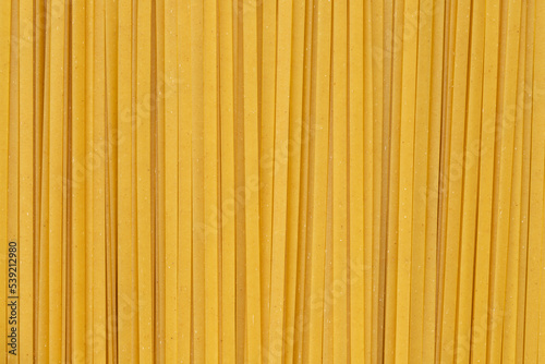 Durum fettuccine noodles background. Close up of raw spaghetti. Full frame of pasta