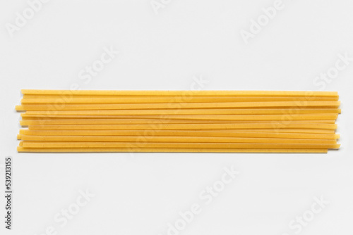 Uncooked durum fettuccine pasta isolated on white background. Raw spaghetti or noodles photo