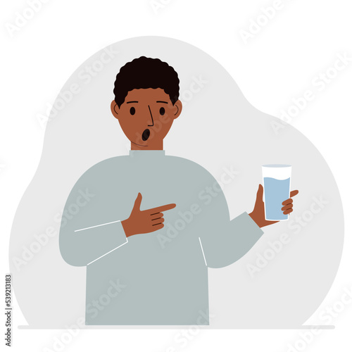 A man holds a glass of water in his hand. The concept of water balance and health.
