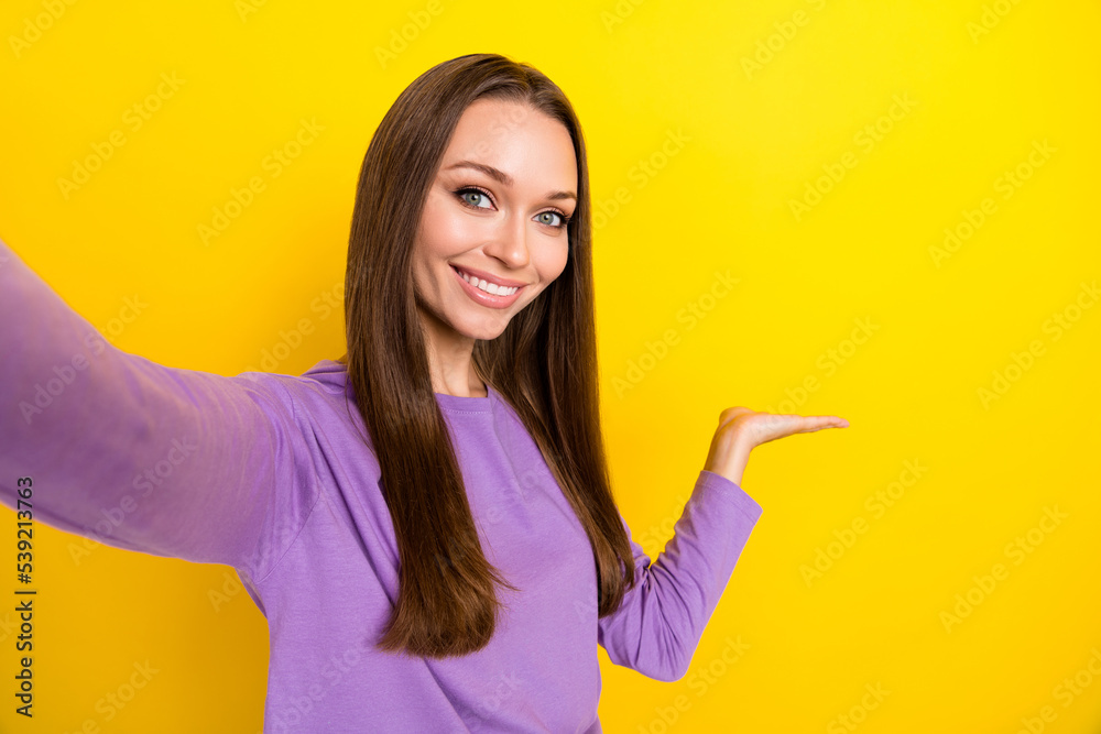 Closeup selfie photo of young successful nice blogger influencer hold palm new promoter object for big sale isolated on bright yellow color background Closeup selfie photo of young successful nice blogger influencer hold palm new promoter object for big sale isolated on bright yellow color background