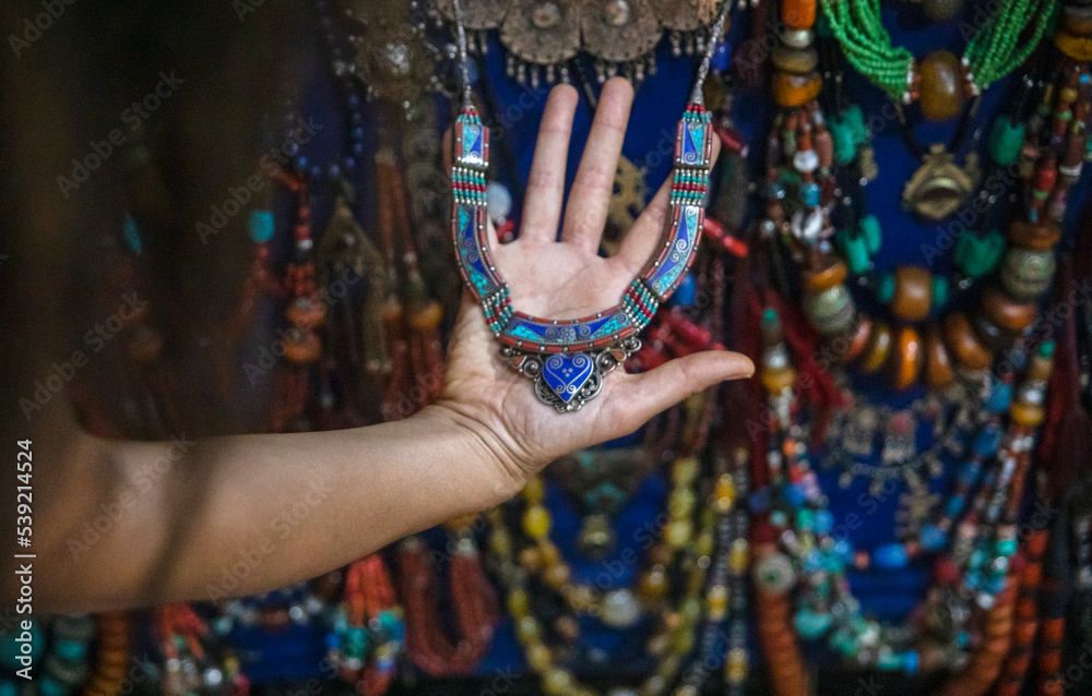 Hand of a female tourist holding a Moroccan costume jewelry pendant in a store in Marrakech in Morocco, this city is full of costume jewelry street stores.
