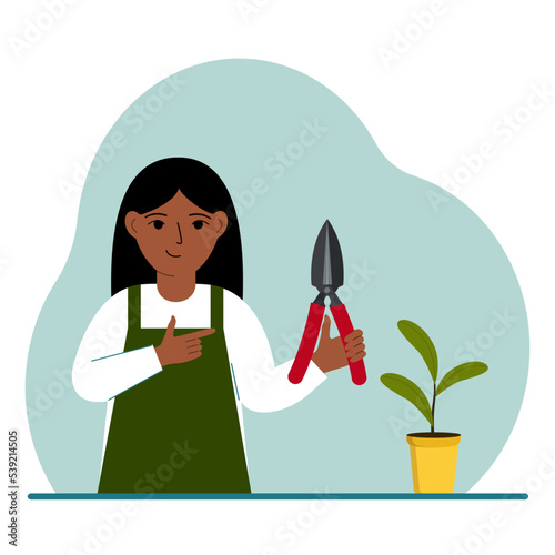 A gardener is a girl in working clothes, he has a pruner in his hand.