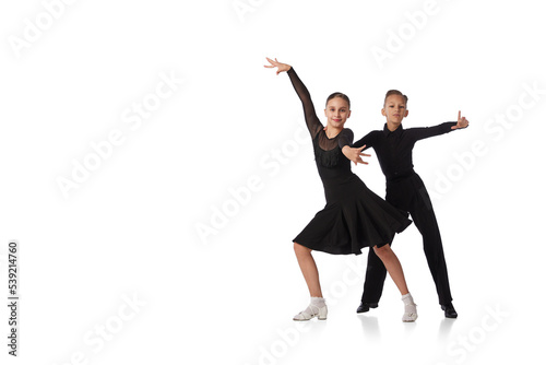 Dance couple. Two kids, school age girl and boy in black stage costumes dancing ballroom dance isolated on white background. Motion, action, hobbies
