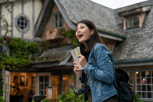 amazed asian Japanese woman visitor holding map and admiring beautiful retro style house buildings in Carmel by the sea the charming coastal town in California usa