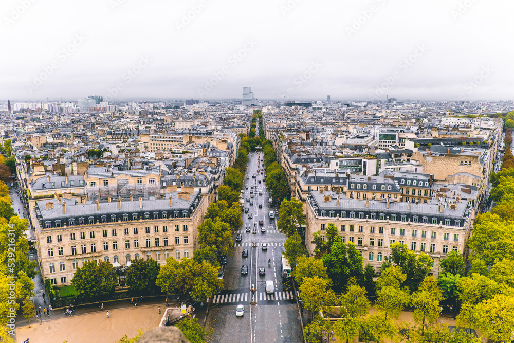 View looking over the city of Paris with cars driving near the Arc de Triomphe