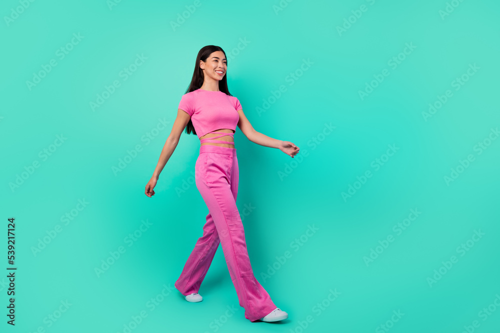 Full length profile side photo of cheerful lady travel go walk wear trend set outfit isolated cyan color background Full length profile side photo of cheerful lady travel go walk wear trend set outfit isolated cyan color background