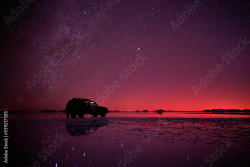 Night star sky at Uyuni salt flats, Bolivia, with a offroad-car parking on the surface.