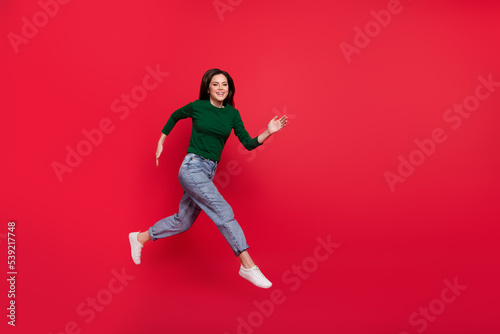 Full length photo of active excited lady run fast rush shopping wear trendy green long sleeve shirt isolated on bright red color background
