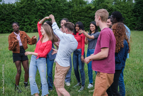 Group of young friends dancing together outdoors in the park and having fun