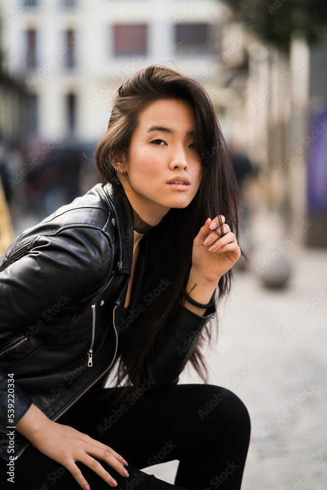 Chinese young and pretty girl in Plaza Mayor of Madrid, Spain, wearing a leather jacket