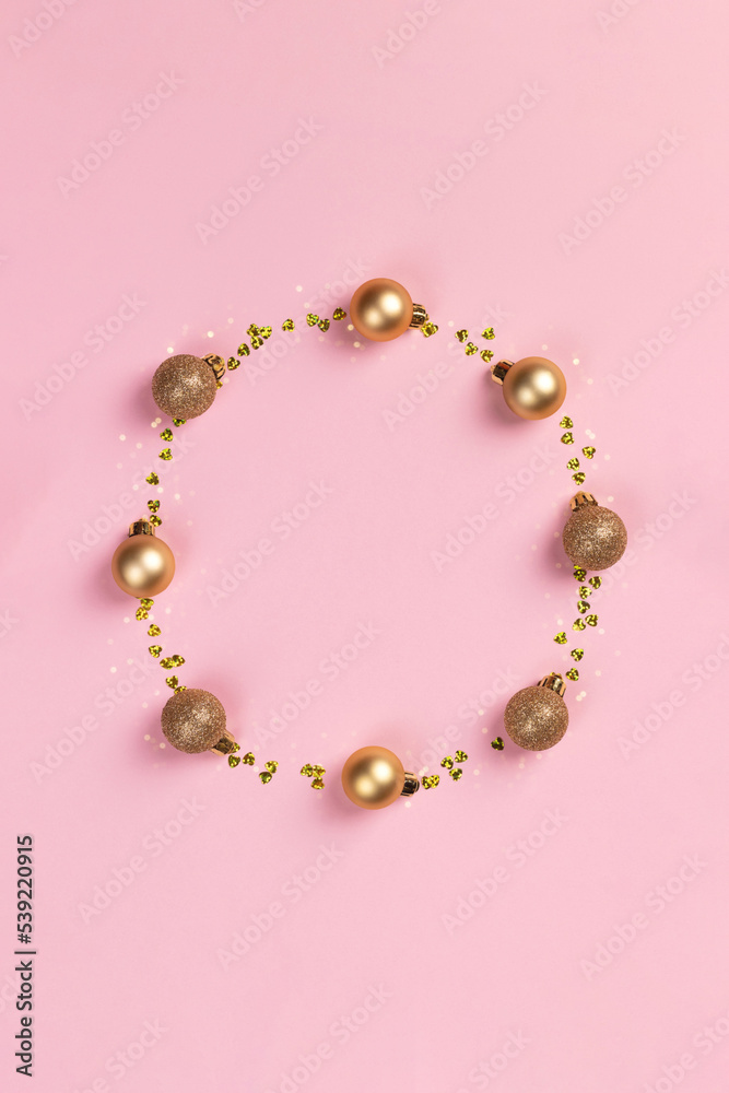 Circle frame of golden Christmas balls and glitter confetti hearts on pink background Circle frame of golden Christmas balls and glitter confetti hearts on pink background