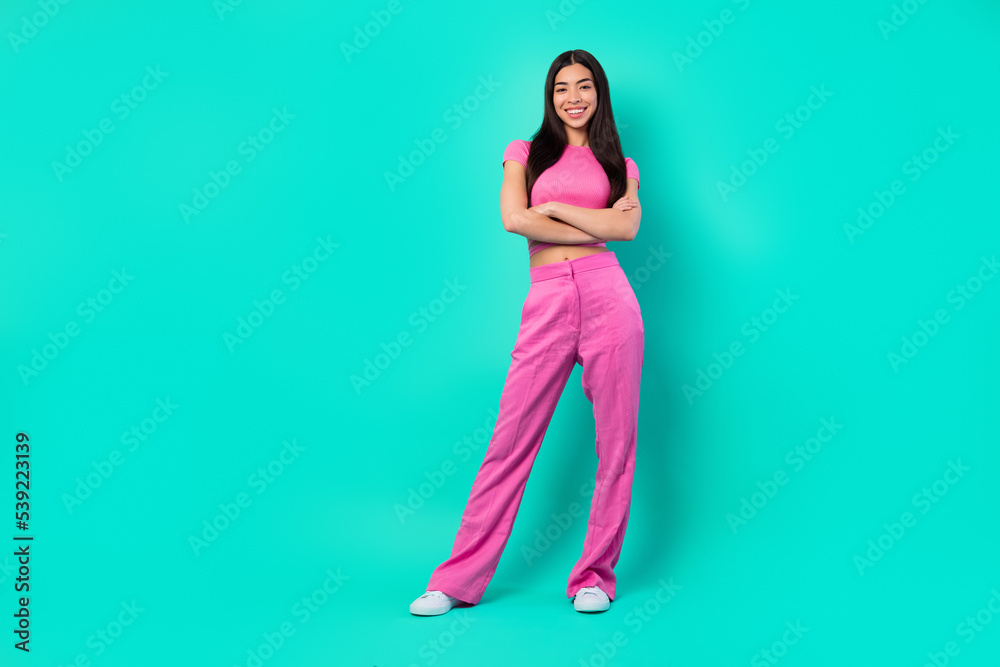 Full length image of stunning stylish young lady with crossed hands wear pink outfit isolated on teal color background