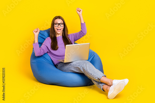 Full length photo of astonished lady sit chair rejoice career promotion success achievement empty space isolated on yellow color background © deagreez