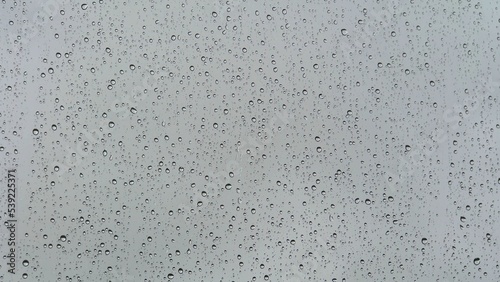 Wet glass. Drops of water on glass. Abstract background. Grey sky. Overcast weather. Water flows. Close-up.