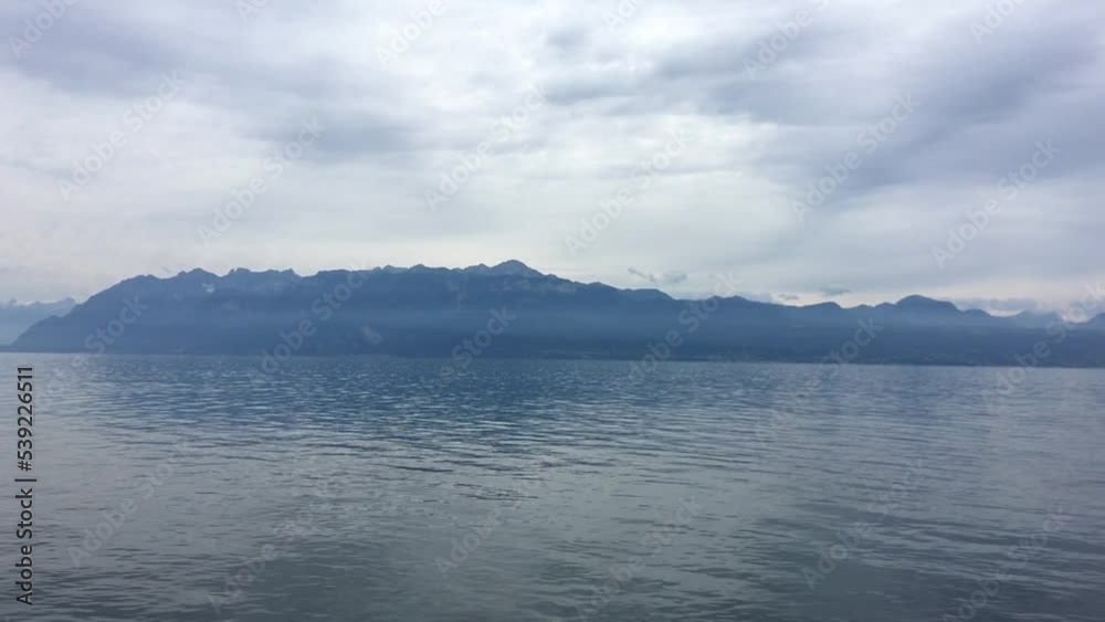 Switzerland Lausanne city landscape. Swiss historical old city walking and touring. Lake in Switzerland Europe with reflections and mountain in the background with trees. Boats on the lake. Cloud sky Switzerland Lausanne city landscape. Swiss historical old city walking and touring. Lake in Switzerland Europe with reflections and mountain in the background with trees. Boats on the lake. Cloud sky