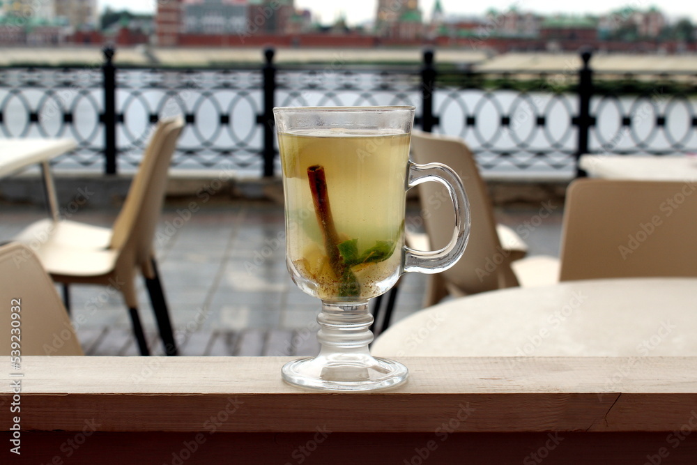 On the veranda of the summer cafe, there is a glass cup with delicious tea on the railing. On the veranda of the summer cafe, there is a glass cup with delicious tea on the railing.