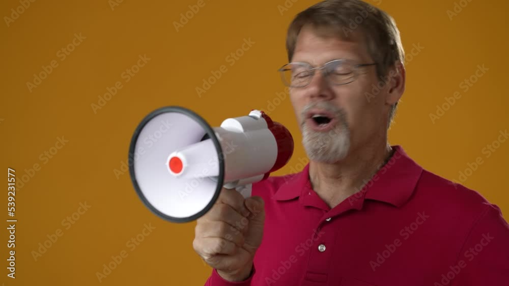 Fun elderly bearded man 50s wears red shirt yells into megaphone announces discounts sale Hurry up isolated on solid yellow background studio portrait Fun elderly bearded man 50s wears red shirt yells into megaphone announces discounts sale Hurry up isolated on solid yellow background studio portrait