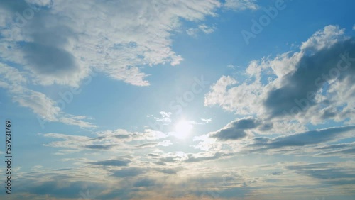 Beautiful sunny blue sky with bright sun light shining through white clouds. Timelapse.