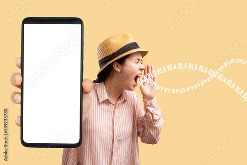 Advertising and smartphone apps. A young Caucasian woman in a straw hat shows a close-up of a phone with a white screen and shouts to someone. Mock up. Concept of online reviews, feedback and shopping photo