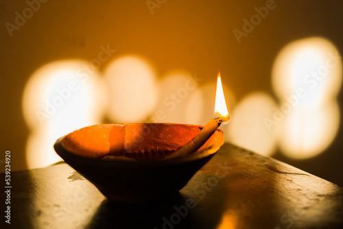diya or earthen oil lamp lit with flame during diwali celebration in india. deepabali or kali puja is celebrated across india as a major festival of light.