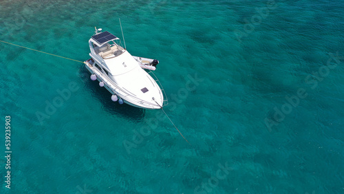 Aerial drone top view photo of small yacht - boat anchored in tropical exotic paradise bay with emerald open ocean © aerial-drone