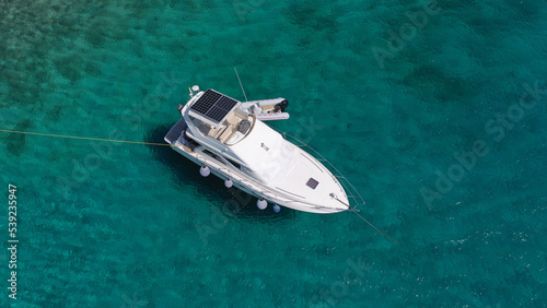 Aerial drone top view photo of small yacht - boat anchored in tropical exotic paradise bay with emerald open ocean
