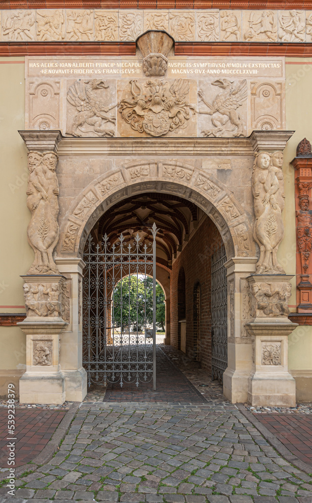 Germany, Wismar - July 13, 2022: Monumental sculpted beige-stone entrance gate to Furstenhof, a renaissance princely court, palace, set in front front facade featuring humans and dragons