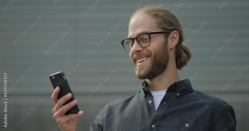 Successful man chatting uses smartphone standing near office building Successful man chatting uses smartphone standing near office building