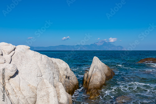 Rock formation with scenic view of holy Mount Athos from Fava sand beach near Vourvourou, Greek peninsula Sithonia, Chalkidiki (Halkidiki), Greece, Europe. Summer vacation at Aegean Mediterranean Sea photo
