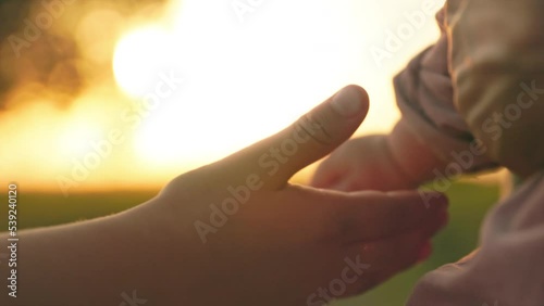 Close-up footage of little baby girl touching hand of brother in blurred background of field during sunset. Tenderness, love, care. Family concept. Outdoor. Village, summertime. Rural scene