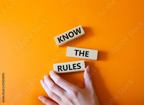 Know the rules symbol. Wooden blocks with words Know the rules. Beautiful orange background. Businessman hand. Business and Know the rules concept. Copy space. photo