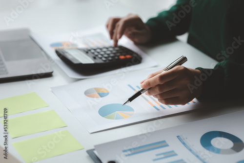 Business woman using a calculator to calculate numbers on a company's financial documents, she is analyzing historical financial data to plan how to grow the company. Financial concept.