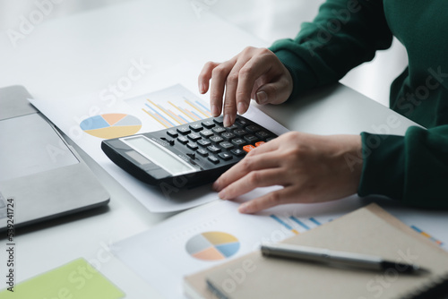 Business woman using a calculator to calculate numbers on a company s financial documents  she is analyzing historical financial data to plan how to grow the company. Financial concept.