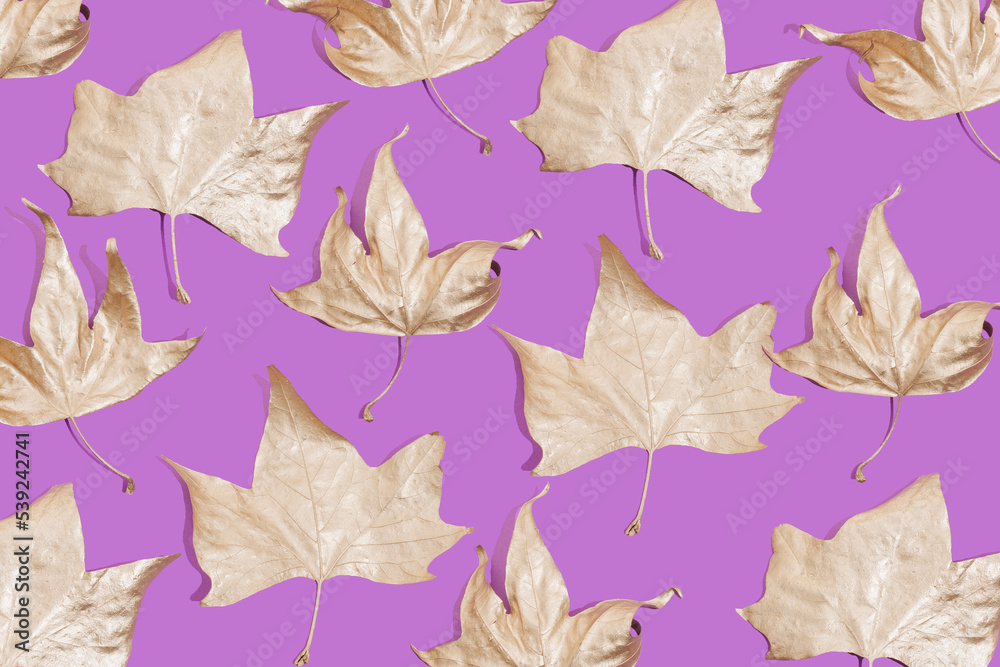 Creative layout of golden autumn leaves on purple background. Flat lay. Season concept.