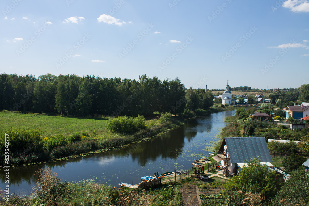 Tourists are rafting on the winding Kamenka river in Suzdal Russia among meadows with grass on a sunny summer bright day and a space for copy