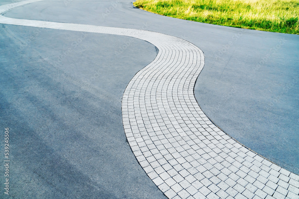 Pedestrian path made of paving stones and asphalt. A beautiful pavement ...